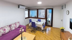 Un espace de vie compact comprenant un canapé, une table à manger avec des chaises et un petit coin cuisine.