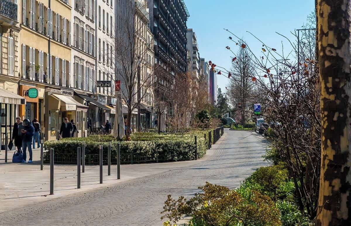 A city street with buildings, a sidewalk, and a parking sign.