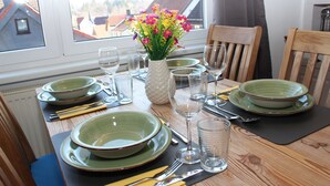 A dining table set with green plates, bowls, cutlery, and a vase of flowers. - Hexenquartier apartment in a central location in Braunlage (Braunlage)