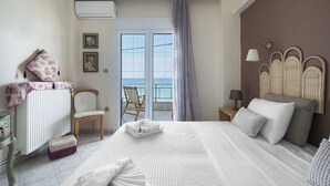 A bedroom with a bed, a chair, a nightstand, and a view of the sea through a glass door. - Pefkohori Blue View by Luxlikehome (Pefkochori Halkidiki)