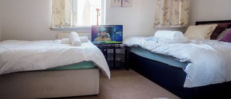 Un dormitorio con dos camas, televisión y una ventana con cortinas.