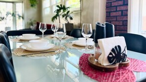 A dining table set with white plates, bowls, and wine glasses, with a pink placemat and a decorative napkin holder. - GSH202-Green Sweet Home-Cozy house in OC (Midway City)