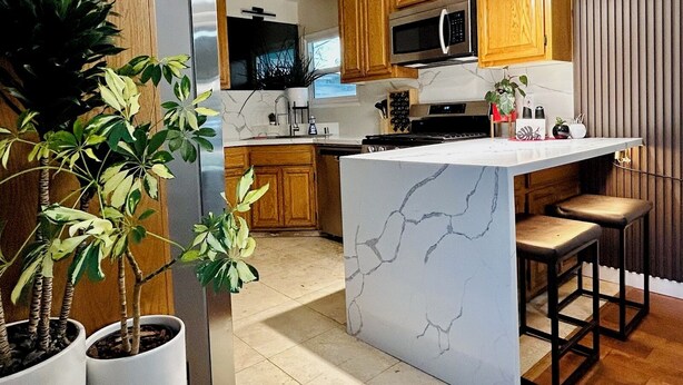 A modern kitchen with wooden cabinets, a marble island, and pendant lighting. - GSH202-Green Sweet Home-Cozy house in OC (Midway City)