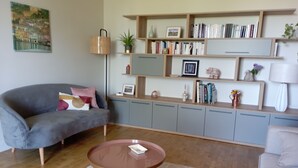 A living room with a grey sofa, a round coffee table, and a bookshelf filled with books and decorative items. - Renovated 1920s house, 15 minutes' walk from town center, quiet location. (Aurillac)