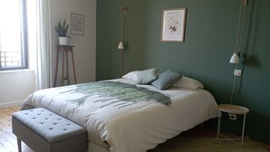 A neatly arranged bedroom with a bed, bedside tables, a bench, and a framed botanical print on the wall. - Renovated 1920s house, 15 minutes' walk from town center, quiet location. (Aurillac)