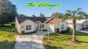 A single-story house with a front entrance, a driveway, and a well-maintained lawn. - The Villages! 2 Squares!-Pool access -Free Wifi-All Amenities-Shopping galore! (Lady Lake)