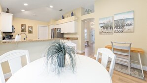 A modern kitchen with white cabinets, a granite countertop, and a dining area with a white table and chairs. - The Villages! 2 Squares!-Pool access -Free Wifi-All Amenities-Shopping galore! (Lady Lake)