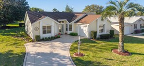 A single-story house with a front entrance, a driveway, and a well-maintained lawn. - The Villages! 2 Squares!-Pool access -Free Wifi-All Amenities-Shopping galore! (Lady Lake)