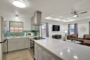 A modern kitchen with a central island, white cabinets, and a microwave. - Peppercorn Teal in Taylor TX (Taylor)