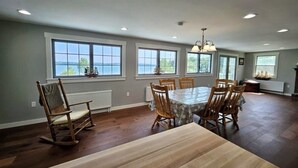 A spacious dining area with a large table and chairs, large windows with a view, and a chandelier.