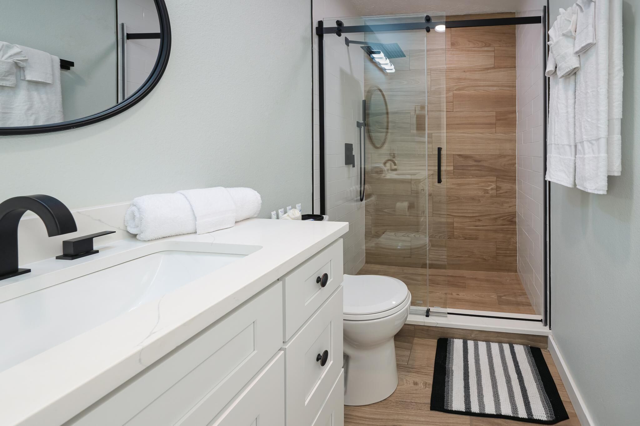 Un bany modern amb una dutxa de vidre, un lavabo blanc i un vàter.