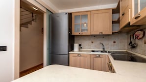 A modern kitchen with wooden cabinets, a stainless steel refrigerator, a sink, and a countertop. - Appartamento Iori (Canazei)