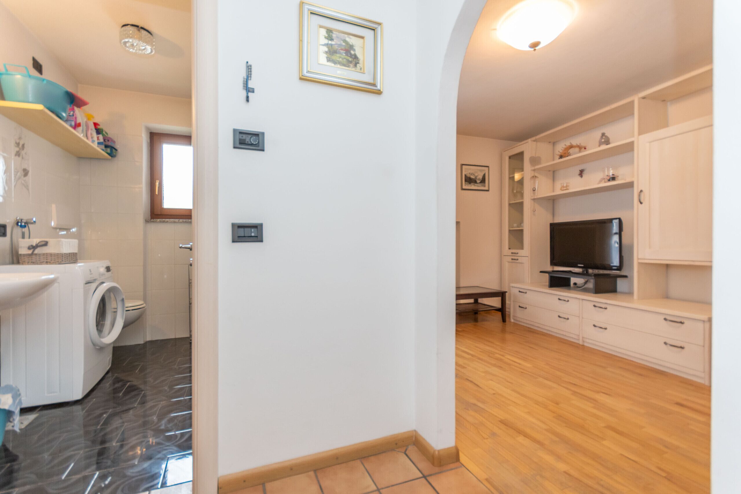 A modern apartment with a kitchen, a living area with a TV, and a bathroom with a washing machine.