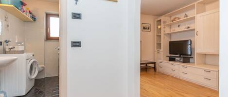 A modern apartment with a kitchen, a living area with a TV, and a bathroom with a washing machine.
