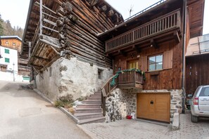 Un edificio tradicional de madera con fachada de piedra, una escalera de madera y un garaje.