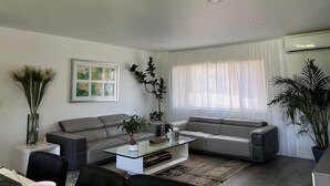 Una sala de estar moderna con dos sofás grises, una mesa de centro de vidrio y una planta grande en maceta.