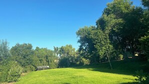 Un campo cubierto de césped con árboles y una pequeña construcción.
