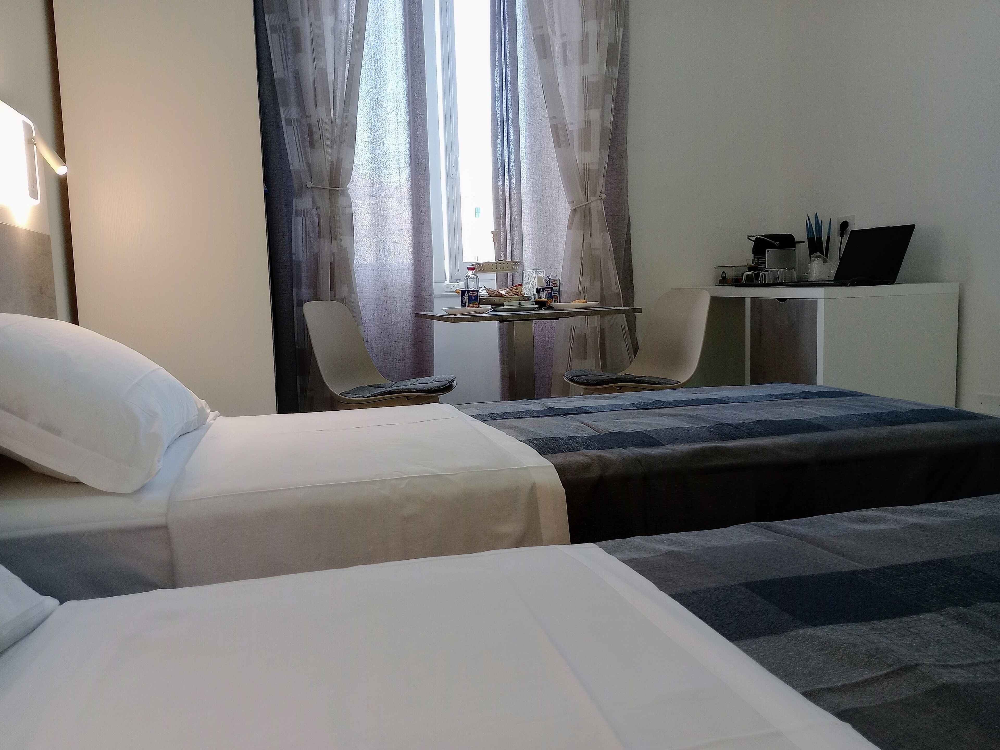 Ett hotellrum med två sängar, ett skrivbord med en bärbar dator och en stol.
