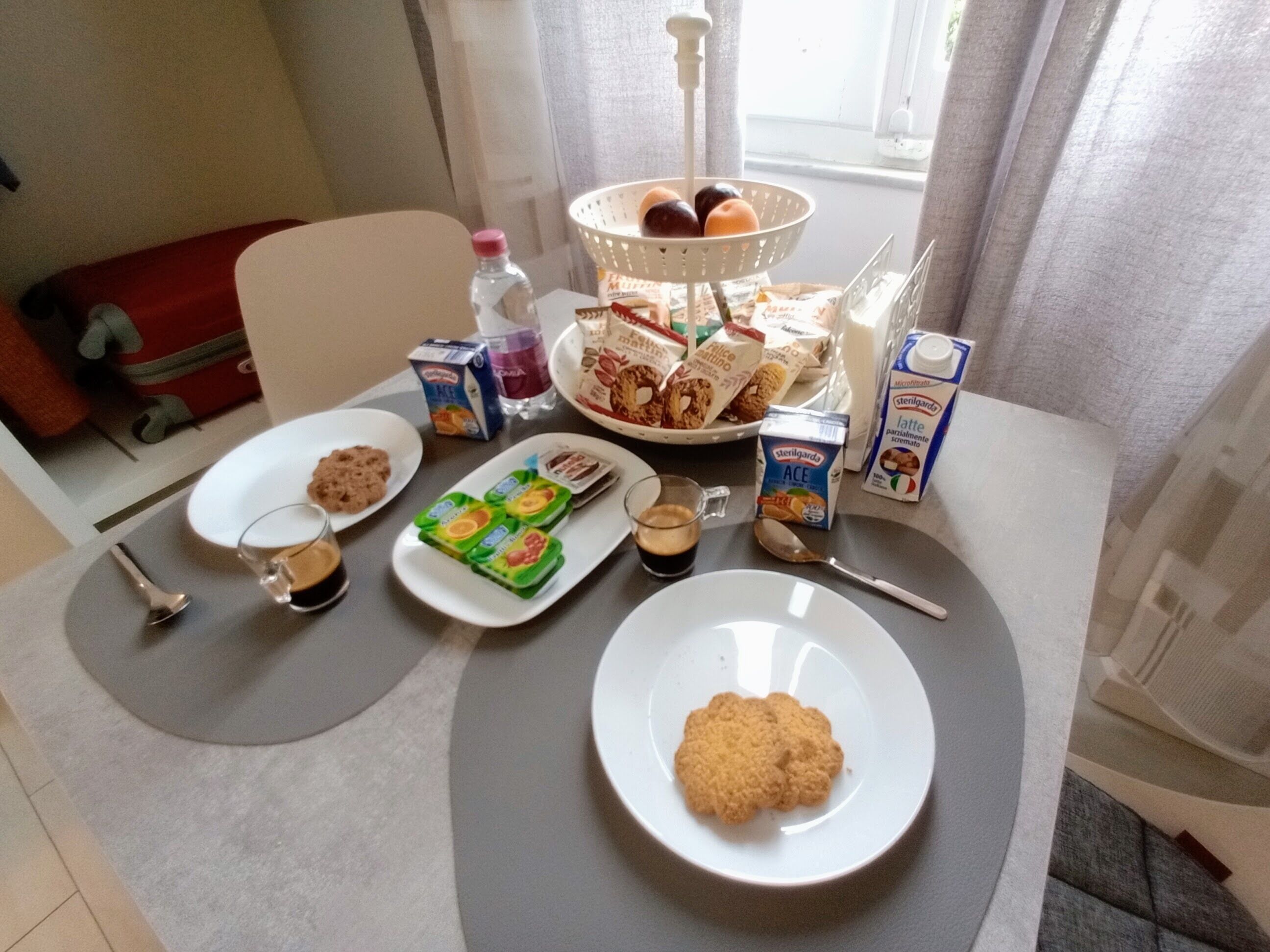 A breakfast table with various food items, including cereal, pastries, and a bottle of water.