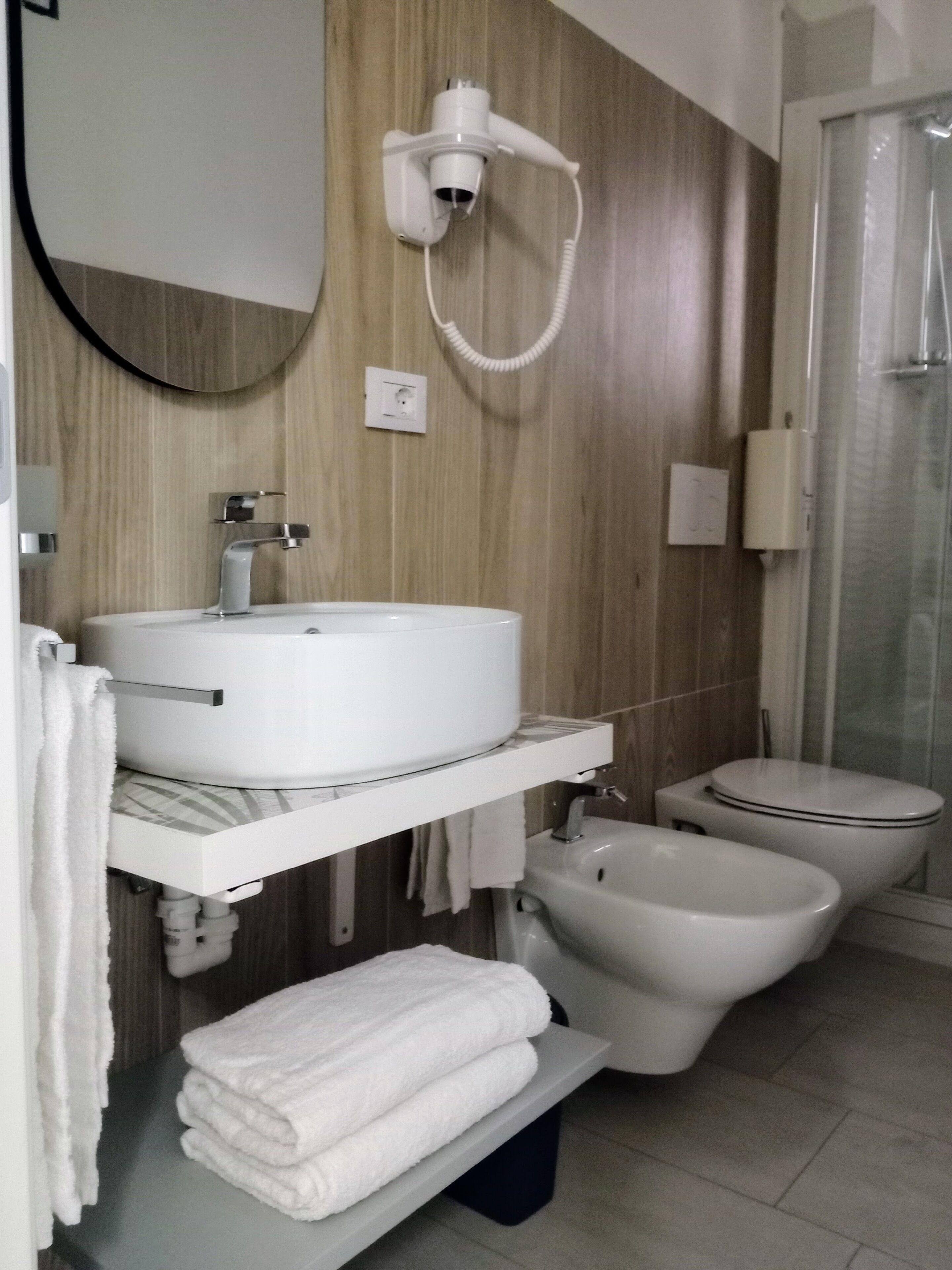 A modern bathroom with a sink, bidet, and toilet.
