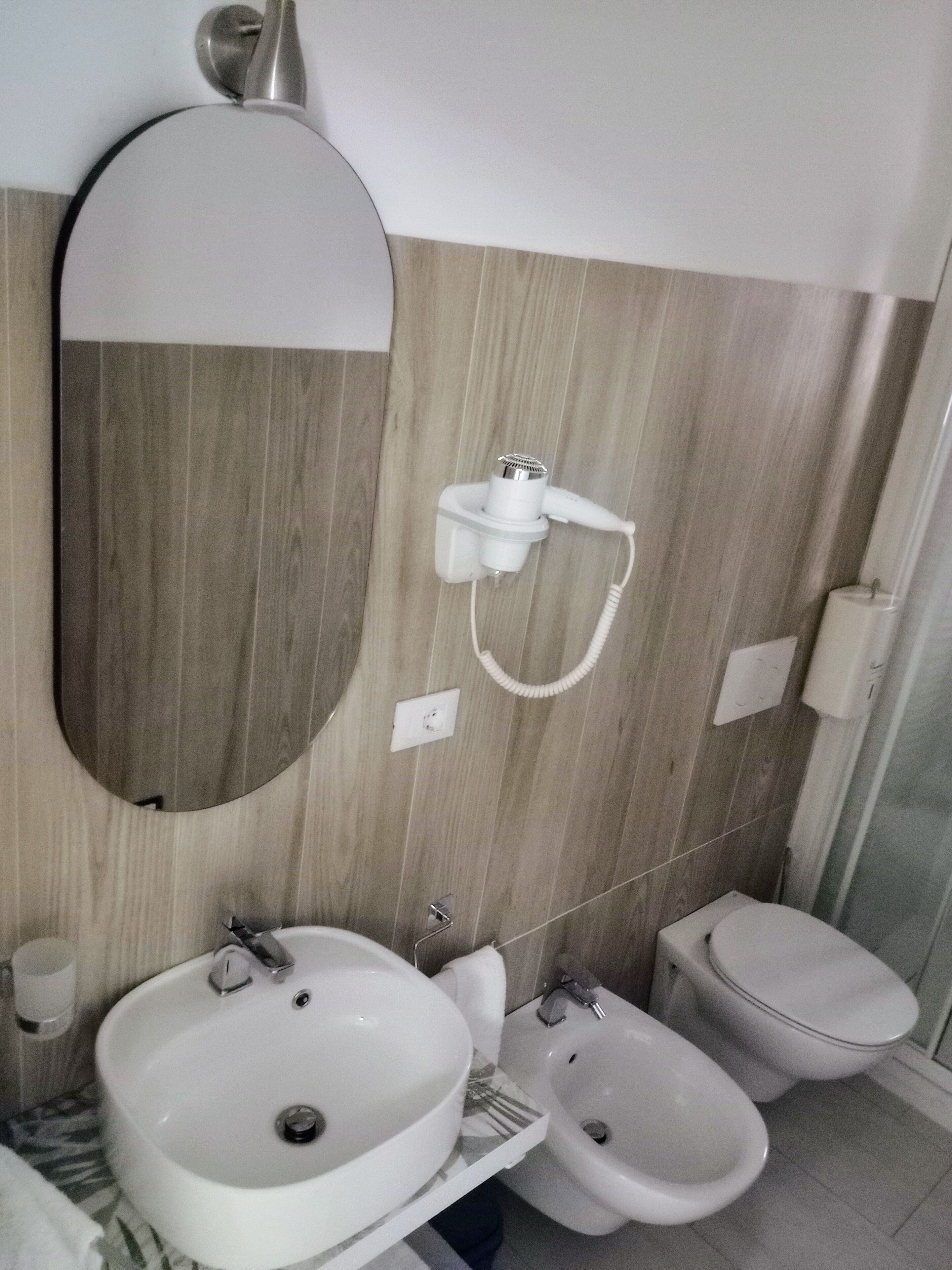 Un bagno con uno specchio grande, un lavandino, un bidet e un water.