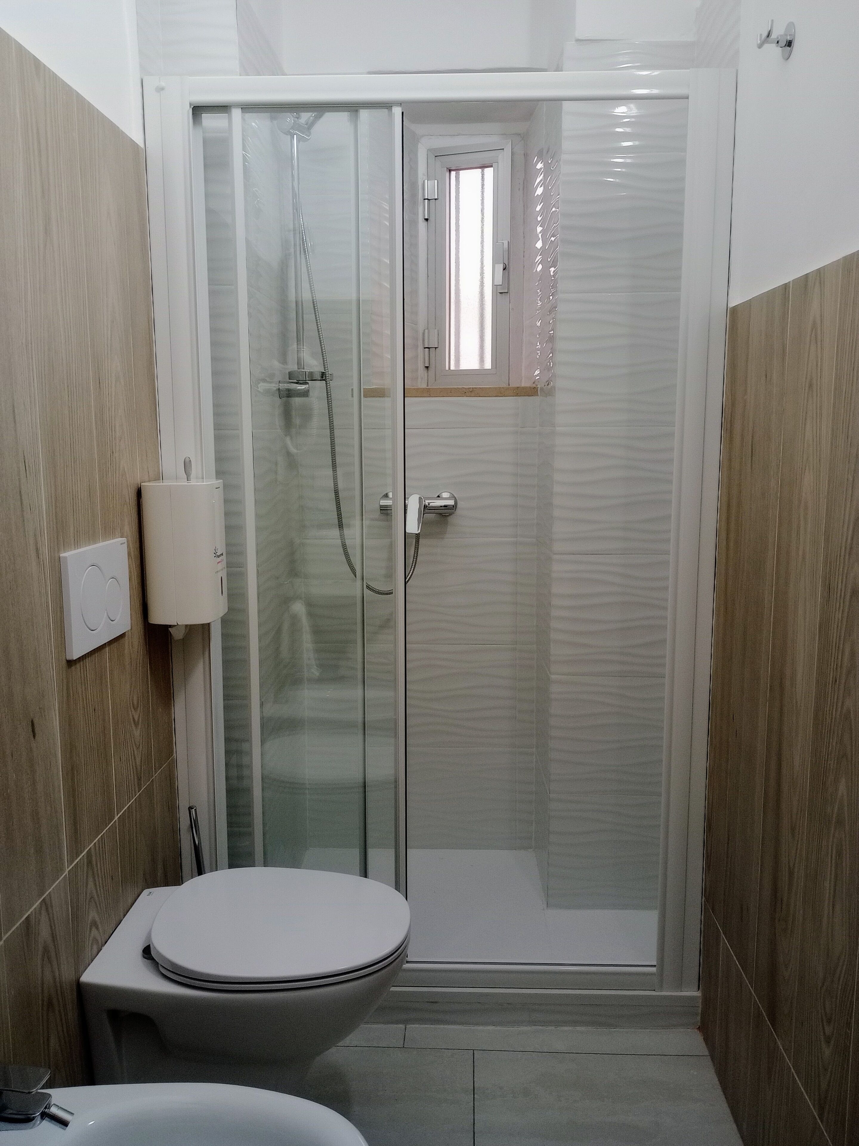 Een badkamer met een toilet, een douchecabine en een wandradiator.