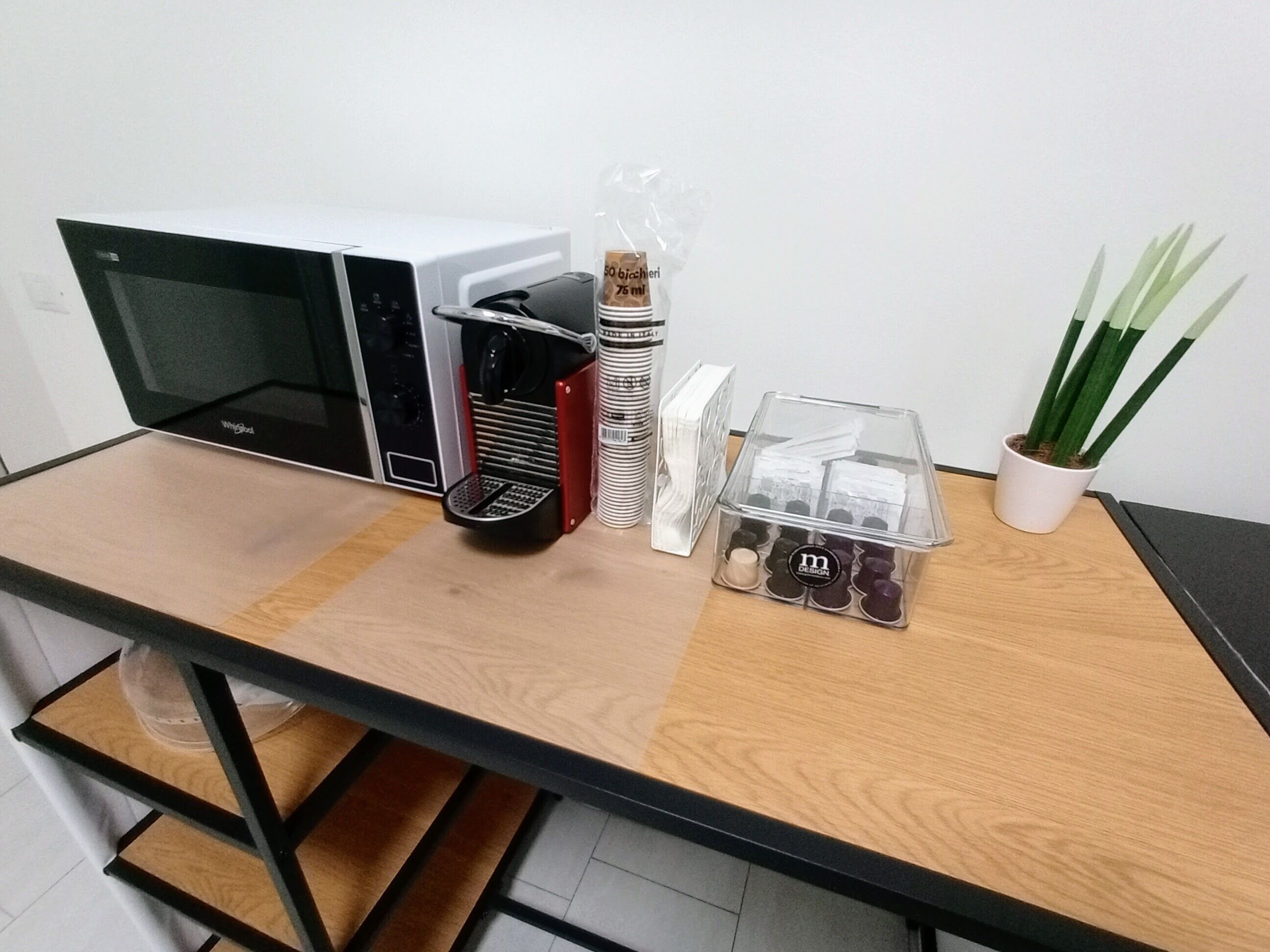 A kitchenette with a microwave, coffee maker, and storage containers.