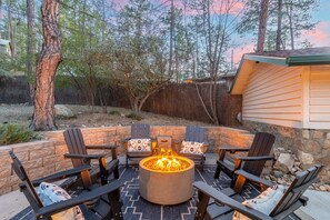 An outdoor seating area with a circular fire pit surrounded by Adirondack chairs. - Pines near Whiskey Row / King Beds / fenced yard (Prescott)