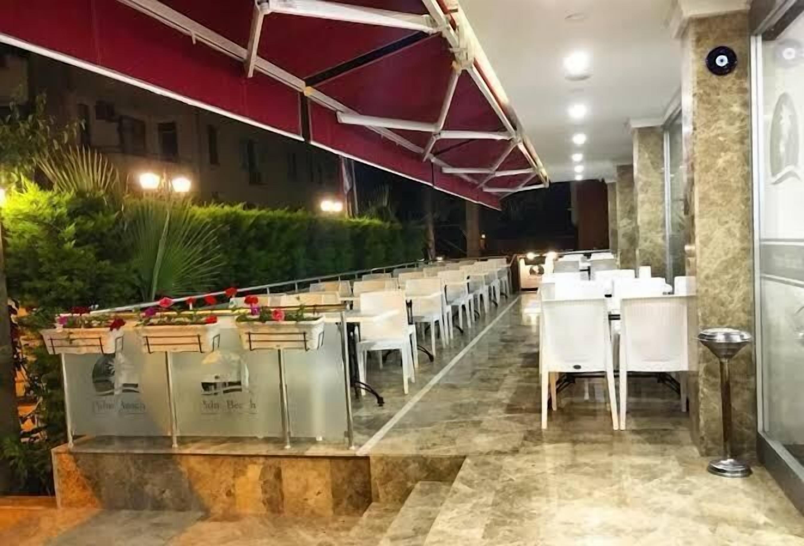A restaurant with a long counter, white chairs, and a red awning.