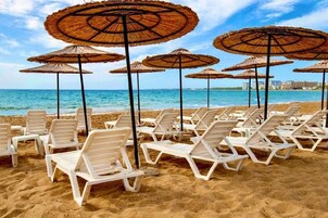Una playa cerca, sillas reclinables de playa, sombrillas