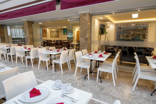 A restaurant with white tables and chairs, arranged in a spacious layout. - PALM BEACH HOTEL (Silifke)