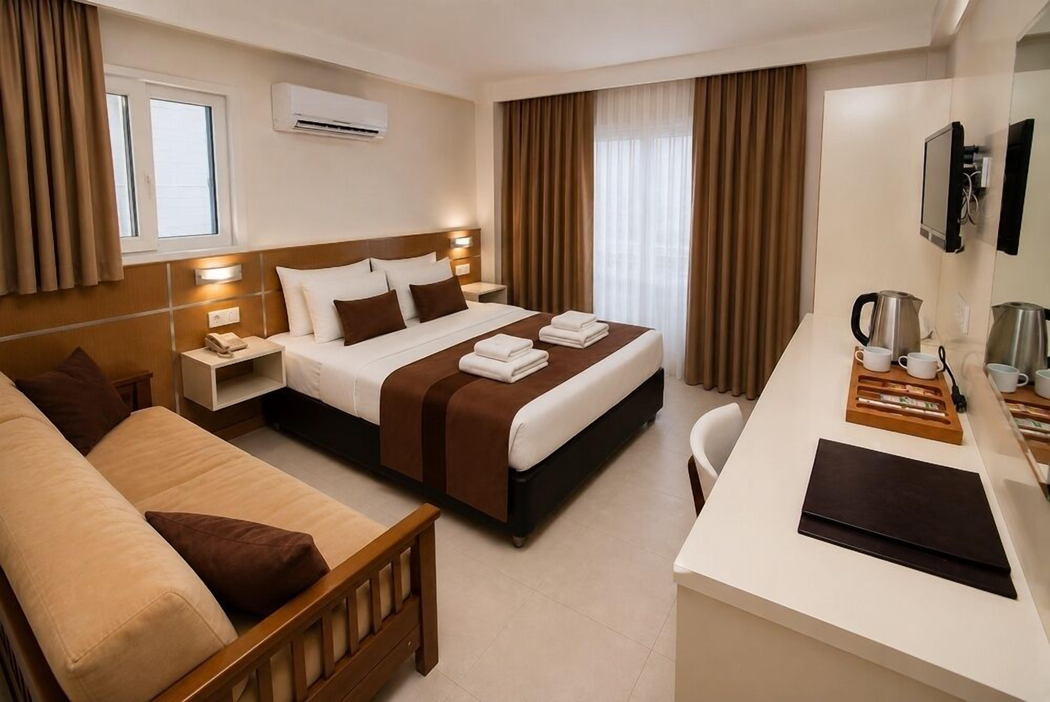 Une chambre d’hôtel avec un lit, un canapé, un bureau et une télévision.
