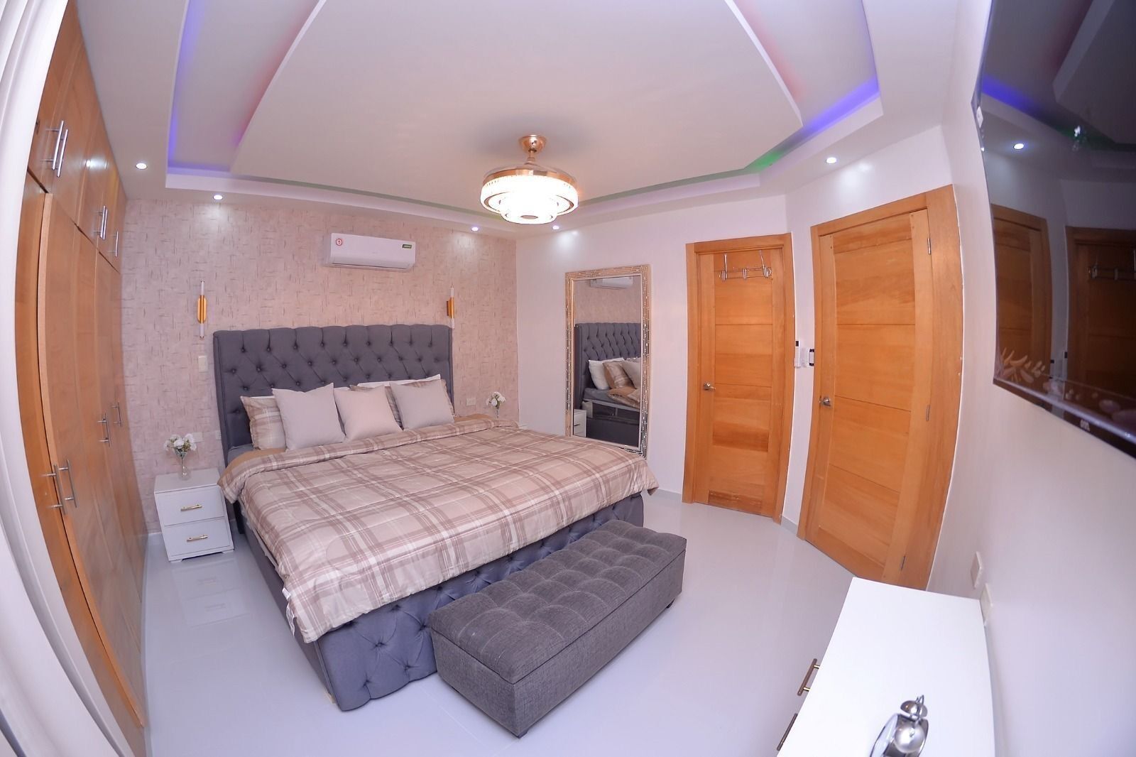 Una camera da letto con un letto grande, un comodino, uno specchio e armadi in legno.