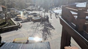 A plaza with outdoor seating and a view of snow-capped mountains.