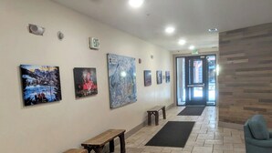 A hallway with benches, artwork on the walls, and an exit sign.