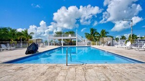 En swimmingpool med ett överbyggt område och solstolar.