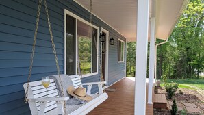 A porch with a swing seat, a glass of drink, and a straw hat. - 3-bedroom house near Deep River, Toyota Megasite, NC Zoo & Zoo Sports Complex (Franklinville)