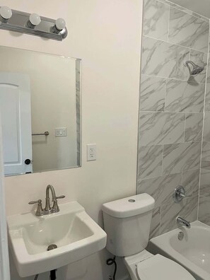 A bathroom with a sink, toilet, and bathtub.