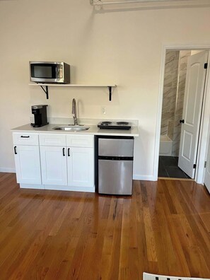 A kitchen with white cabinets, a microwave, a coffee maker, a sink, and a dishwasher.