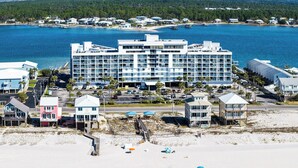Un hotel frente a la playa con varias construcciones, una playa de arena y una vista despejada del océano.