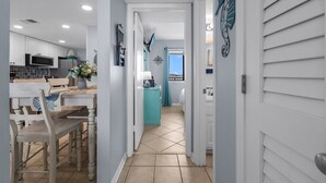 Una cocina con gabinetes blancos, un microondas y un comedor con mesa y sillas.