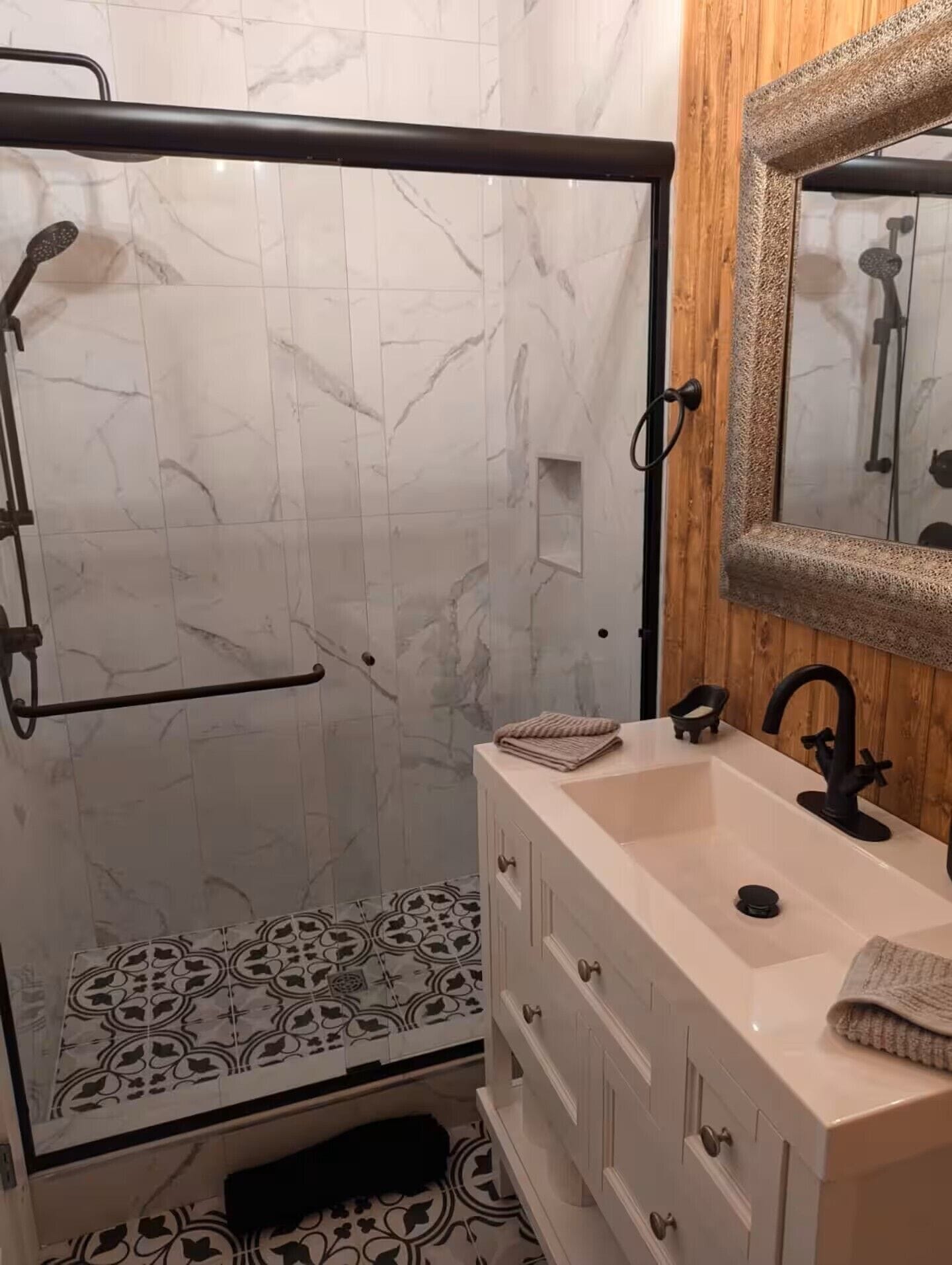 A bathroom with a shower, a sink, and a mirror.