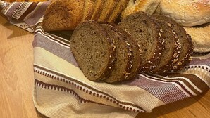 A variety of breads and pastries on a wooden table with a striped cloth.