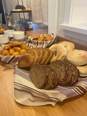 A variety of breads and pastries on a wooden table with a striped cloth.