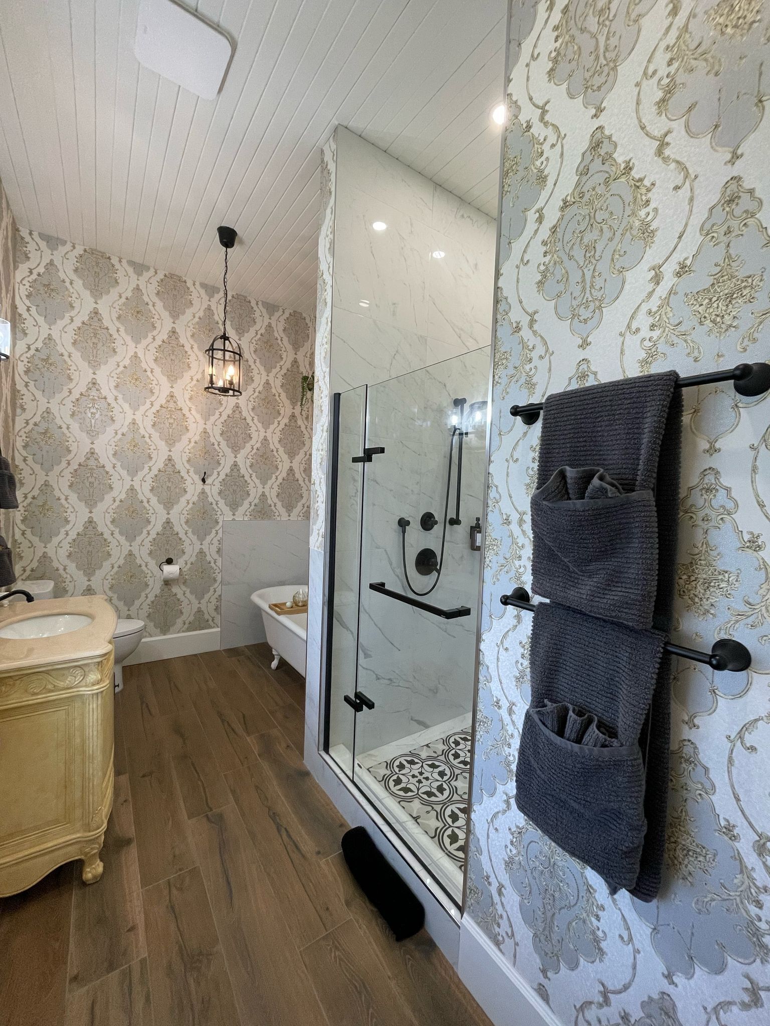 Une salle de bain avec une douche à parois de verre, des toilettes blanches et un lavabo de style rétro.