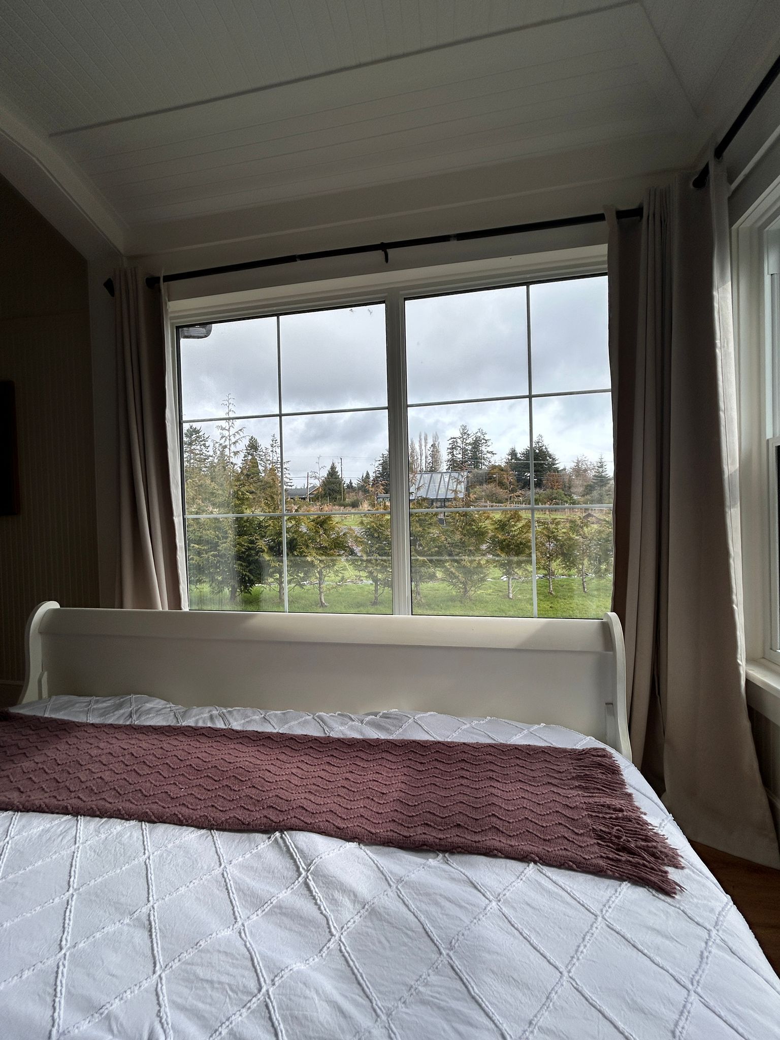 A bedroom with a bed, a window, and curtains.