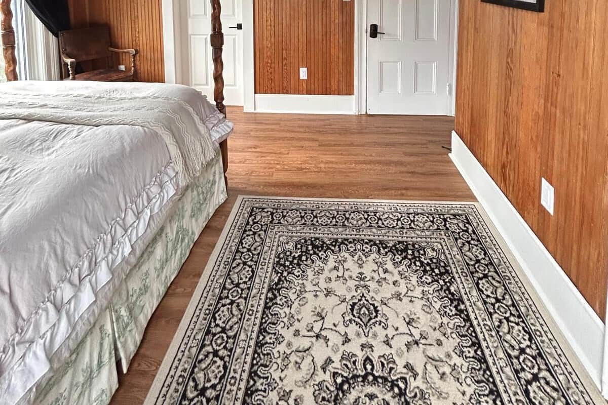 A room with a bed, a chandelier, a door, and a framed picture on the wall.