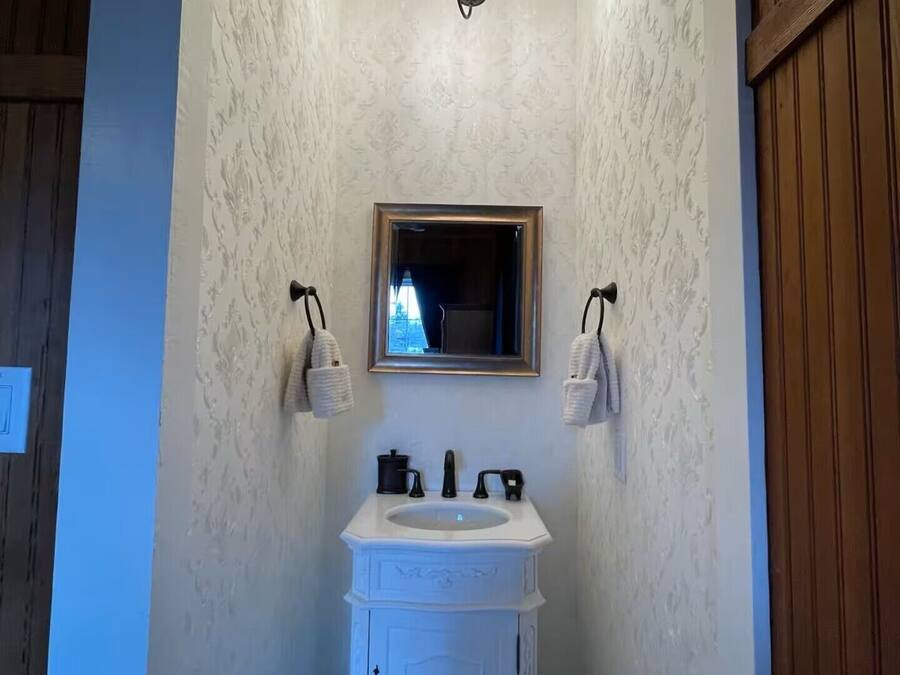 Un baño con tocador blanco, espejo y candelabro.