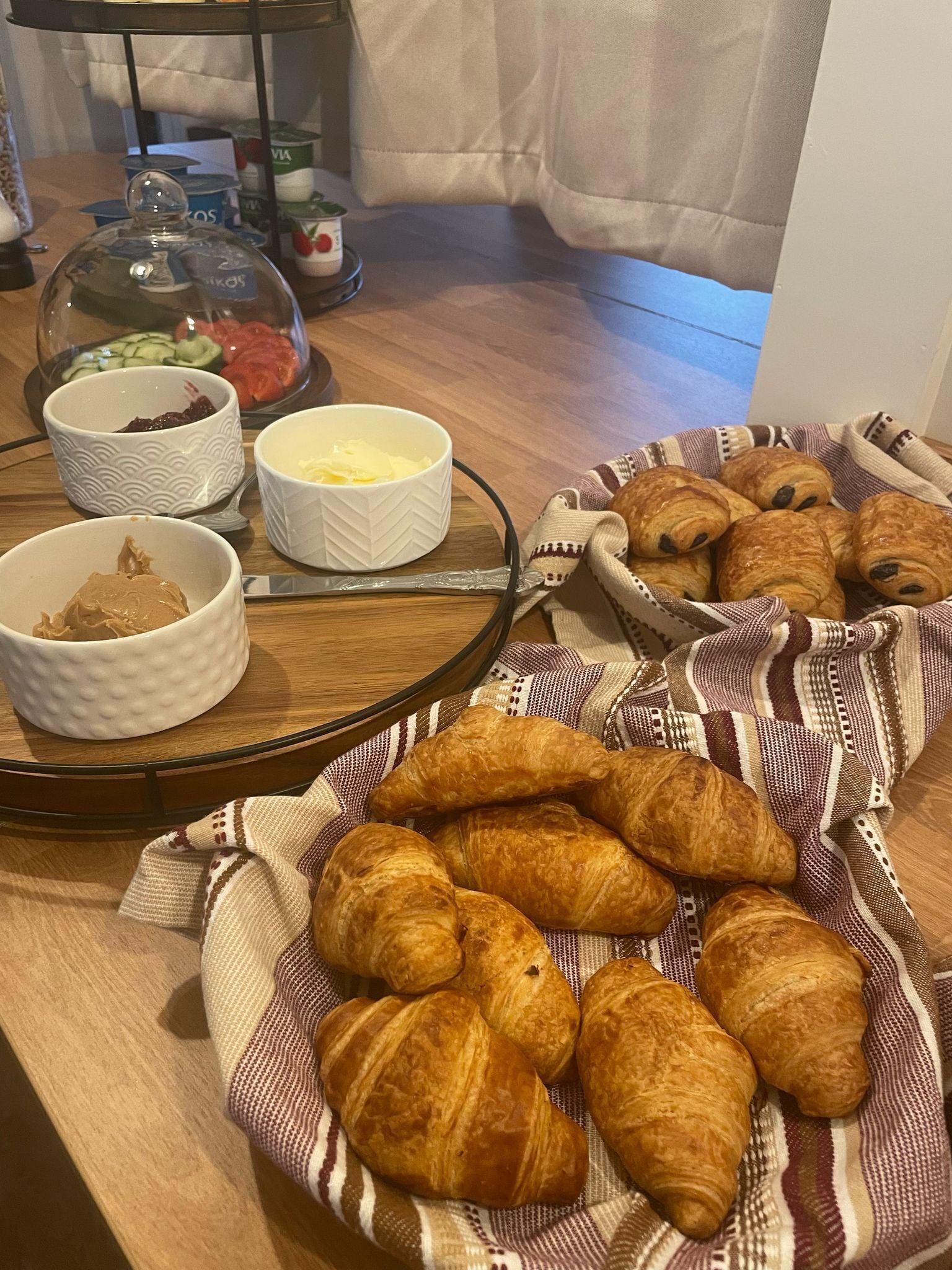 A breakfast table with croissants, butter, jam, and yogurt.
