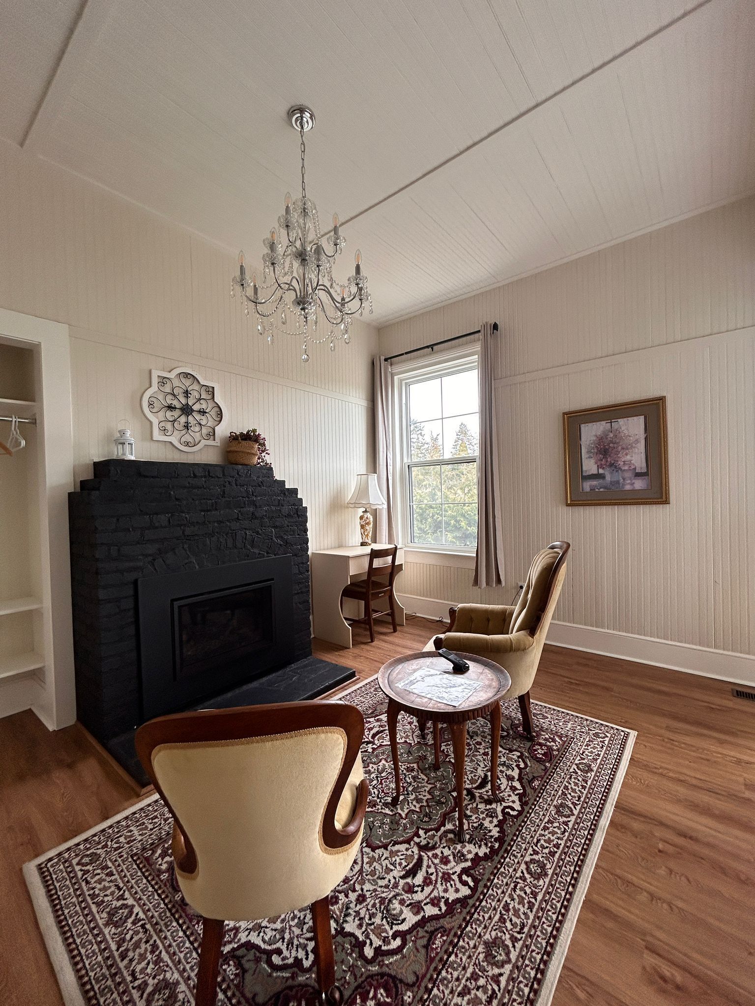 A living room with a fireplace, a chandelier, a dining table, and a patterned rug.